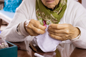 Senior woman sewing a homemade face mask during the Covid-19 pandemic