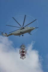 Large transport helicopter carries parts for a construction site. Helicopter in the blue sky with clouds © Brunbjorn