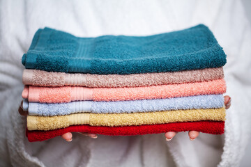Woman in a white coat holding a stack of colored towels