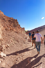 Pessoas caminhando pelo deserto do Atacama, Chile, embaixo de sol forte e paisagem seca.