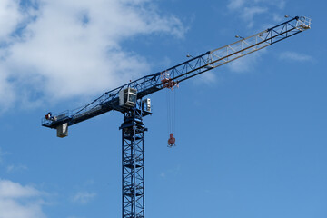 construction crane on the cloudy blue skies background. Sunny daytime. Noon. Equipment