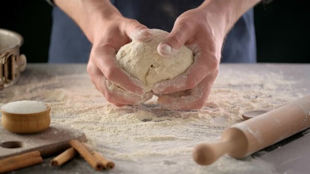 Baker hands are making dough with flour. Chef knead dough on kitchen table. Process preparation homemade pastry.