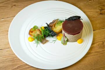 Liver pate with baked potatoes and fresh herbs .On a white plate. On a rustic wooden background