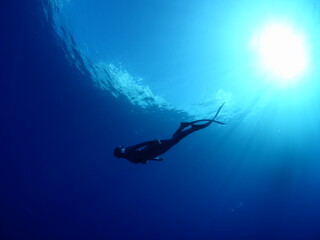 Obraz na płótnie Canvas free diver apnea woman underwater blue water with sun beams and rays
