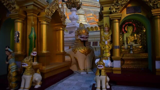 Tilt down shot of statues by golden pagodas against sky - Yangon, Myanmar