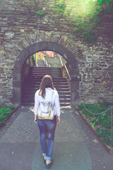 Young woman tourist standing, walking back in front of the famous old city stone gate entrance