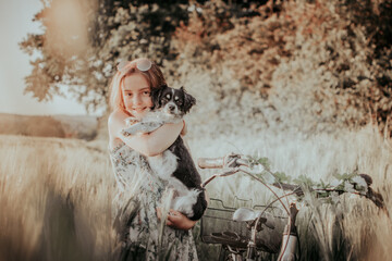 Junges Mädchen mit einem Hund auf dem Arm steht im Feld