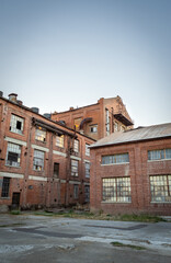 Fototapeta na wymiar Abandoned multi-story brick factory building with broken glass windows.