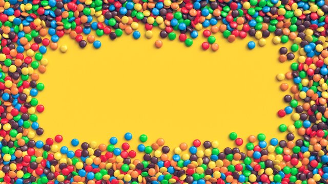 Colorful coated chocolate candies frame on yellow background