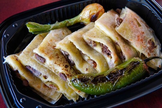 Closeup Shot Of Quesadillas With Roasted Green Chili Peppers And Onion In A Plastic Container