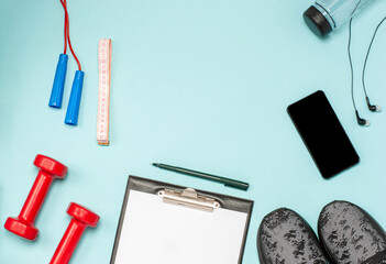 Flat lay of sports equipment for fitness on a blue background.