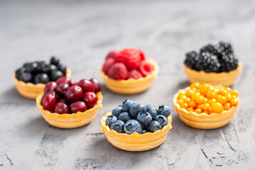 Homemade tartlets from shortcrust pastry with different ripe berries