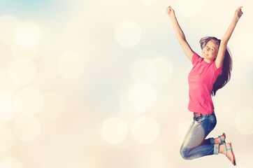Fototapeta na wymiar Cheerful young woman jumping on pastel background