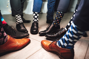 Close up of men legs wearing formal shoes and funny colorful socks. Seven friends feet in circle...