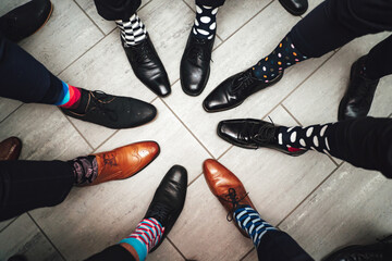 Men feet in shoes and funny colorful socks in circle composition. Top view of 8 legs wearing formal...