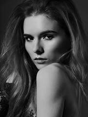 Fototapeta premium Beautiful passion look young woman with volume hair style on dark studio background. Closeup portrait. Black and white.
