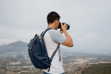 Obraz premium joven fotógrafo con mochila azul realizando fotos con una cámara a la naturaleza