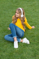 Fototapeta premium sounds of nature. relax on green grass. spring leisure time. happy childhood. kid in headset. happy little girl listen favorite song. kid beauty and fashion. teen girl listen music. education concept