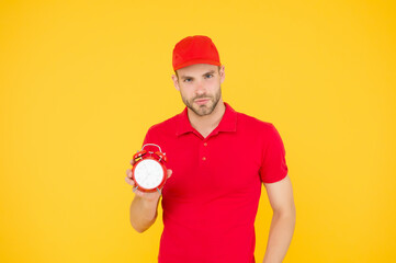 Delivery courier with clock. Delivery man holding clock. Shipping services. Post office. Online shopping. Will deliver at agreed time. Timeliness guarantee. Promptness and punctuality. Delivery time