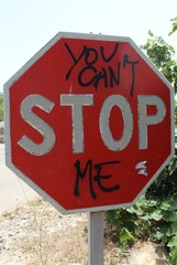 Road sign with graffiti daubed in black paint 