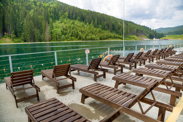 Obraz premium Row of empty wooden beach chairs near water.