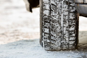 Close-up of car wheels rubber tire in deep snow. Transportation and safety concept.
