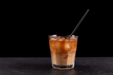 Iced latte coffee in a transparent misted glass. Dark background, copy space