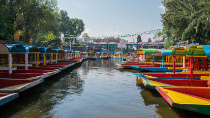 Naklejka premium Traditional Mexican trajinera boat in the Xochimilco channels in Mexico City. Lake full of colorful boats