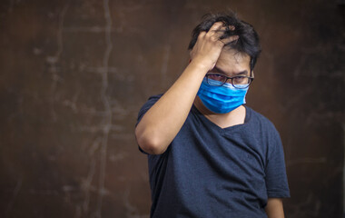 Corona virus, or Covid-19, is spreading all over the world. Portrait of an Asian Man wearing a black oil mask, anti-virus, or anti-Covid-19. Feeling stressed