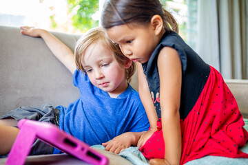 Caucasian boy and Asian girl play and learn on electronic  tablet device