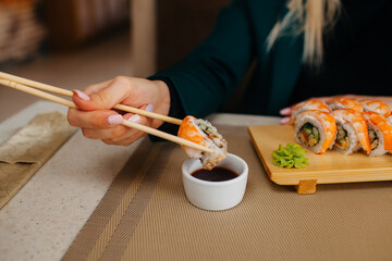 girl dips roll in soy sauce close up
