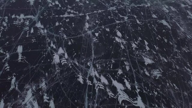 Aerial view of two cars standing on frozen lake Baikal near Shamanka mount. Beautiful patterns on ice. Khuzhir, Olkhon island, Siberia, Russia. 