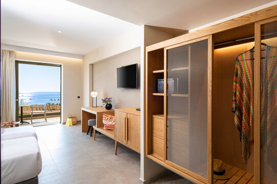 Wooden wardrobe cabinet furniture in white in modern minimalistic style interior of double hotel room with open sea view terrace