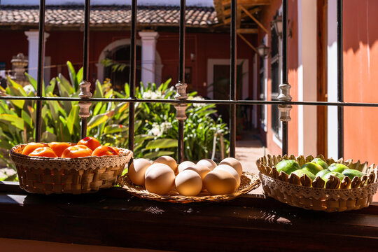 En la ventana de la cocina antigua hay tres cestas con tomates, huevos y limones.