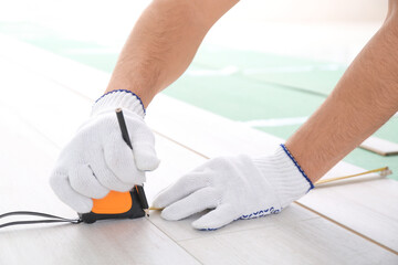 Obraz na płótnie Canvas Carpenter installing laminate flooring in room