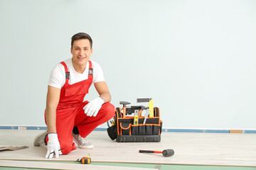 Carpenter installing laminate flooring in room