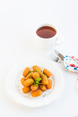 Traditional Turkish Pastry Dessert,Tulumba in the white porcelain plate with a cup of tea.Garnished with pistachio powder.Vertical image