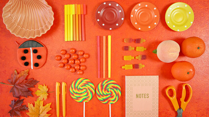Orange aesthetic Back to School theme creative layout flat lay with school supplies, candy and stationery, autumn theme on textured orange background.