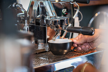 Closed up barista preparing cappuccino using modern machine at coffee shop