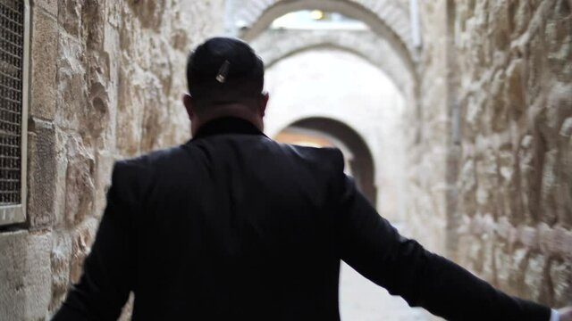 Jewish man walks down the narrow street of Jerusalem, touches Holy City walls