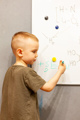 boy writes with marker on white blackboard