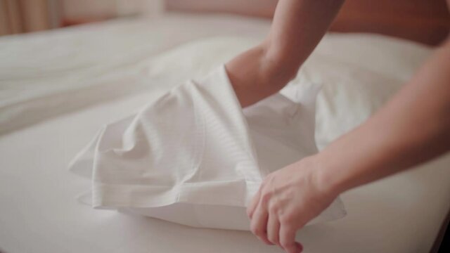 Hotel service maid lady making small white bed pillow in chambermaid