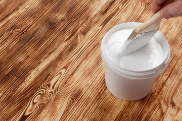 a can with white paint and a brush lie on a brushed surface, the brush is lowered into a can
