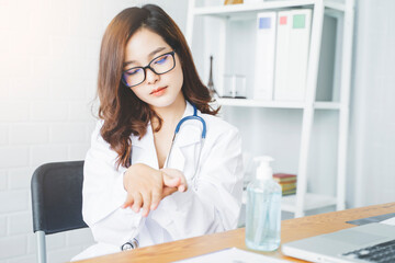 Medical healthcare beautiful Asian doctor using hand sanitizer gel disinfectant rubbing washing hands staying clean hygiene from infectious disease bacteria germs, working in hospital modern office