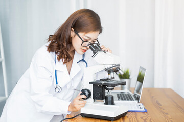 Medical health clinic beautiful Asian doctor using microscope examining testing cells experiment diagnosing patient, researching virus disease DNA working in hospital facility laboratory modern office