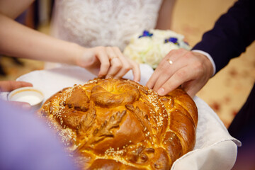 Obraz na płótnie Canvas The bride and groom break the loaf. The traditional greeting of the newlyweds. Wedding bread. festive baking