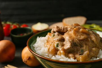 Tasty beef stroganoff and rice in bowl on table, closeup