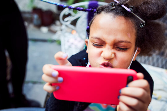 Young Mixed Race Girl Having Hair Braided in Backyard
