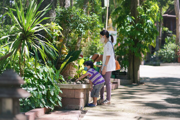 young woman and her little child in the tropical garden during sunny day in summer season