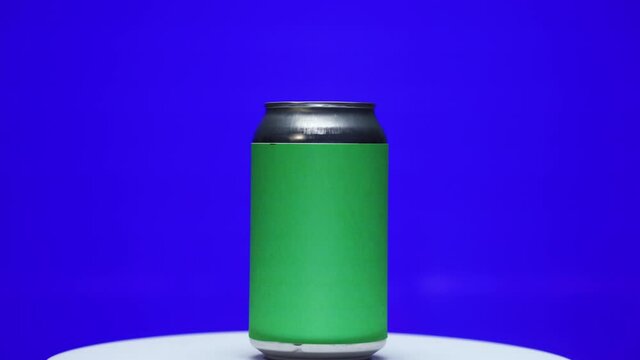 Soda or beer can with chroma green screen label spinning on turntable stand with chroma key blue background zoom in